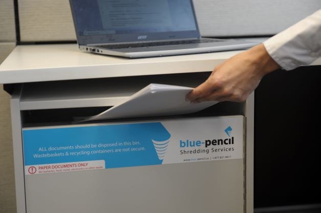 Person placing confidential documents into secure Blue-Pencil shredding console.